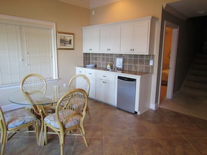 Cozy kitchen area with a dining table and chairs, featuring white cabinetry and a tiled backsplash.