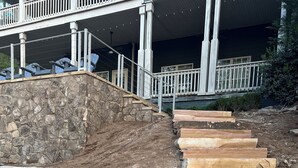 Eine steinerne Stützmauer mit einer Treppe, die in eine angelegte Grünfläche führt.
