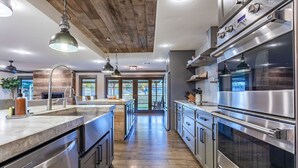 Une cuisine moderne dotée d’appareils électroménagers en acier inoxydable, de planchers en bois et de luminaires suspendus.