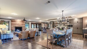 Un vaste espace de vie doté d’une cheminée, d’une table à manger avec des chaises et d’une cuisine équipée d’appareils électroménagers modernes.
