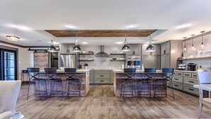 Une cuisine moderne dotée d’un îlot central, de tabourets de bar et de luminaires suspendus.