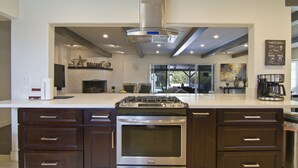 A modern kitchen with a central island, built-in oven, and stainless steel range hood. - Large Resort House - Peloton, BBQ island, Firepit, Pool, Spa! (Anaheim)