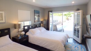 A hotel room with two beds, a large window, a sliding glass door leading to an outdoor area with a pool. - Large Resort House - Peloton, BBQ island, Firepit, Pool, Spa! (Anaheim)