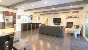 A modern kitchen with dark wooden cabinets, a stainless steel refrigerator, and a bar area. - Large Resort House - Peloton, BBQ island, Firepit, Pool, Spa! (Anaheim)