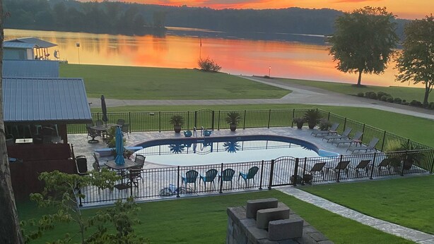 A lakeside patio with outdoor seating and a stone wall. - Outdoor family time on the patio, at the pool-pool house, or on the boat dock! (Lexington)