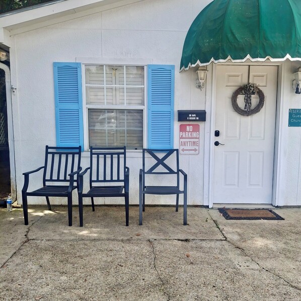 A building with blue shutters, a 'NO PARKING ANYTIME' sign, and two black chairs in front. - Charming Downtown Fairhope Cottage – Walk to Everything! (Fairhope)