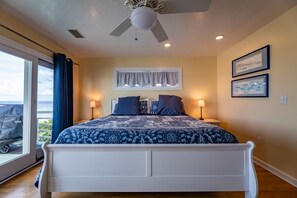 Une chambre à coucher avec un grand lit, deux lampes de chevet, un ventilateur de plafond et une fenêtre avec des rideaux.