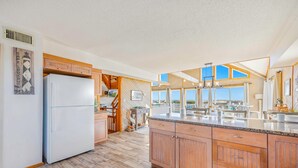 Een ruime keuken met houten kastjes, een groot eiland en uitzicht op de omgeving.