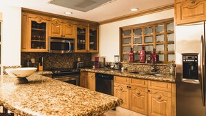 A kitchen with granite countertops, wooden cabinets, a stainless steel refrigerator, and a built-in microwave.