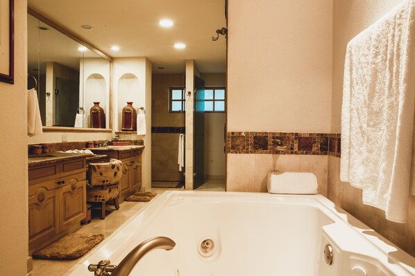 Une salle de bain avec une baignoire, un lavabo et un miroir. On peut voir un porte-serviettes et un espace douche.