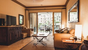 A spacious living room with a sofa, a coffee table, a TV, and a dining area with chairs and a table.