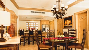 A spacious dining area with a round table, multiple chairs, and a chandelier.