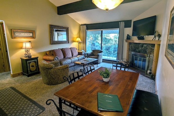 Living room with sofa bed, wood fireplace, dining table, and balcony w/ gas BBQ