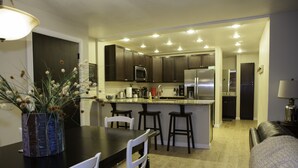 A modern kitchen with dark cabinets, stainless steel appliances, and a central island with bar stools.
