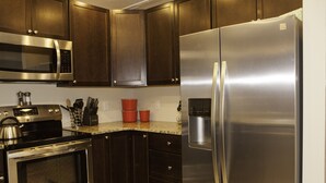 A modern kitchen with stainless steel appliances, dark wooden cabinets, and granite countertops.
