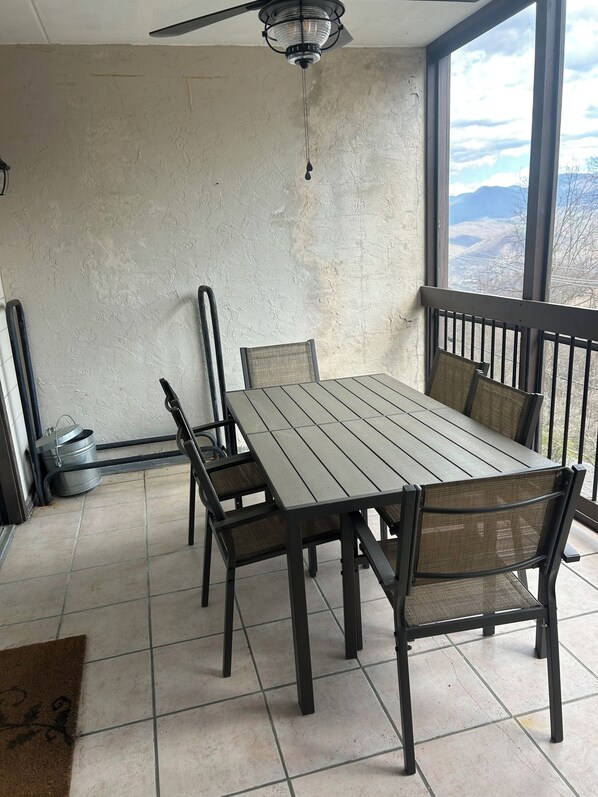 A dining area with a table and chairs, a ceiling fan, and a view of mountains through large windows.