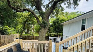 A wooden deck with outdoor furniture, a large tree, and a house with a white railing. - A Marsh View from this 3BR 2 Bath House (Tybee Island)