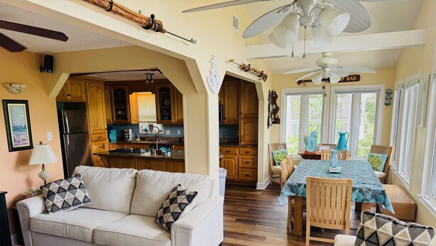 A cozy living room with a sofa and armchairs, a dining area with a table and chairs, and a kitchen with wooden cabinets and a refrigerator. - A Marsh View from this 3BR 2 Bath House (Tybee Island)