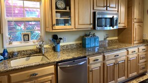 A kitchen with wooden cabinets, a stainless steel microwave, and a granite countertop. - A Marsh View from this 3BR 2 Bath House (Tybee Island)