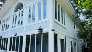A two-story building with large windows, a sign reading "1010", and a small porch area. - A Marsh View from this 3BR 2 Bath House (Tybee Island)