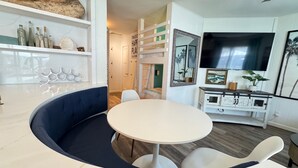 A modern kitchen with a round dining table, white cabinets, and a built-in bench.