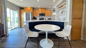Een moderne keuken met een centraal eiland, witte stoelen en houten kastjes.