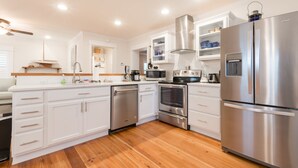 Una cocina moderna con armarios blancos, electrodomésticos de acero inoxidable y suelo de madera.