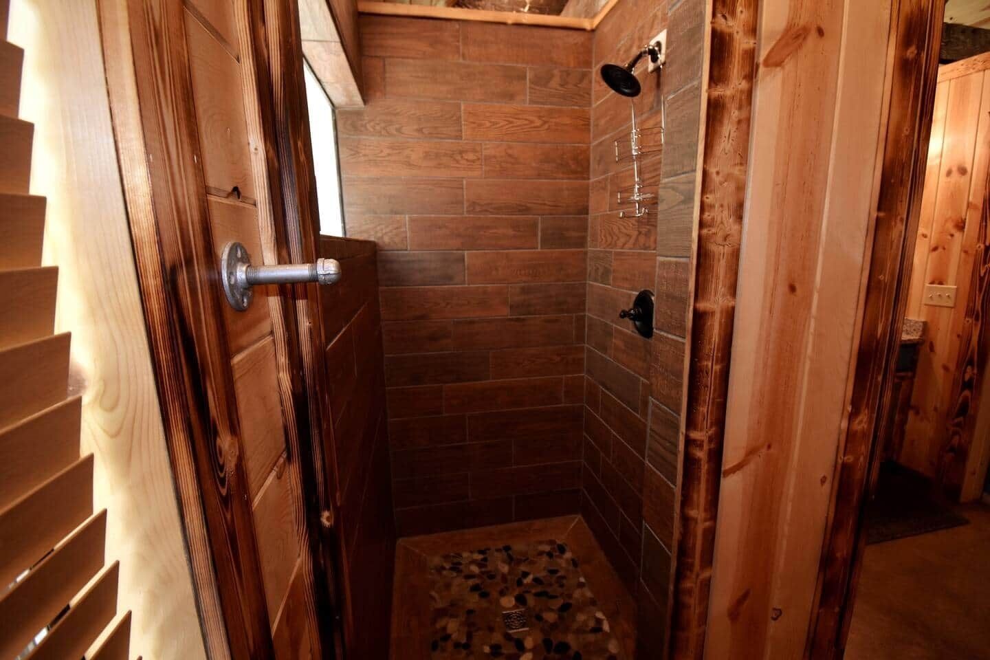 Un intérieur en bois avec un espace douche doté de murs carrelés et d’un pommeau de douche.