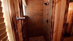 A wooden interior with a shower area featuring tiled walls and a showerhead. - Ole Blue (Broken Bow)