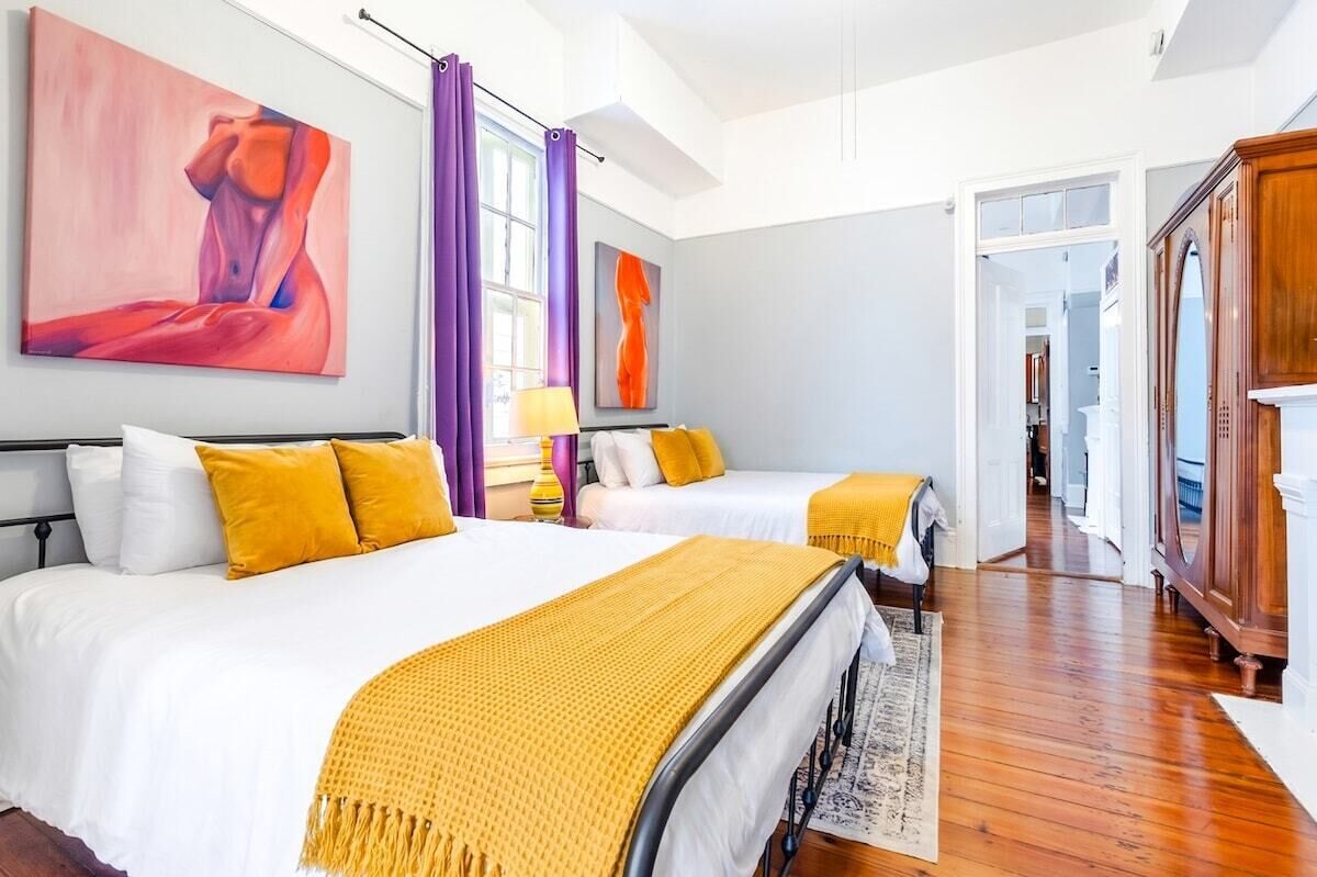 A hotel room with two beds, a wardrobe, and artwork on the walls.