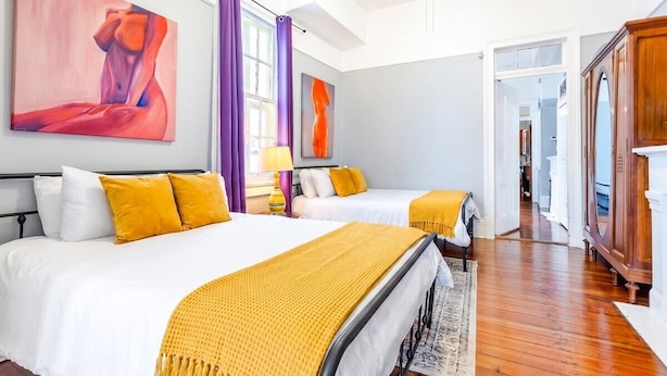 Une chambre d’hôtel avec deux lits, une armoire et des œuvres d’art accrochées aux murs.