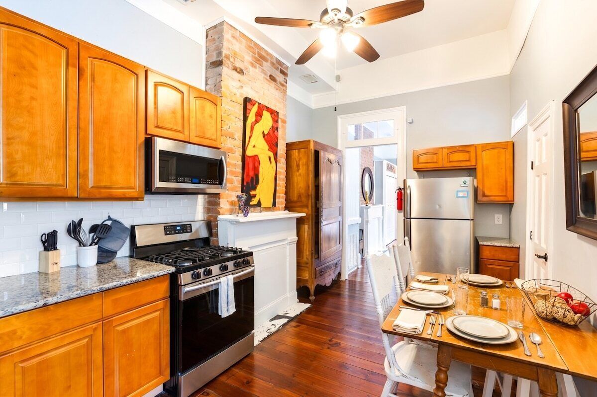 A kitchen with wooden cabinets, a stove, microwave, and a ceiling fan.