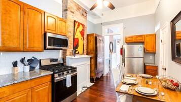 A kitchen with wooden cabinets, a stove, microwave, and a ceiling fan.
