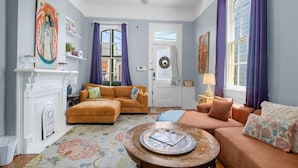 Un salon avec une cheminée, deux canapés, une table basse et des œuvres d’art accrochées aux murs.