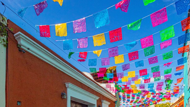 A cobblestone street with colorful flags hanging overhead.