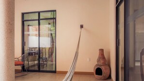 A room with a hammock, a sliding glass door, a tiled floor, and a rustic pot.