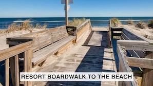 A wooden boardwalk leading to the beach with a signpost at the end. - Oceanfront Condo w/ Private Sundeck, Resort Pool, Elevator, and Beach Access (Rodanthe)