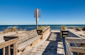 Un paseo marítimo de madera que conduce a la playa, con un cartel al final.