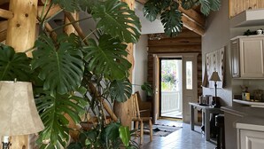 A spacious kitchen with wooden beams, a dining area, and large potted plants.