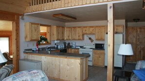 Una cocina con armarios de madera, una isla central, microondas, estufa y refrigerador.