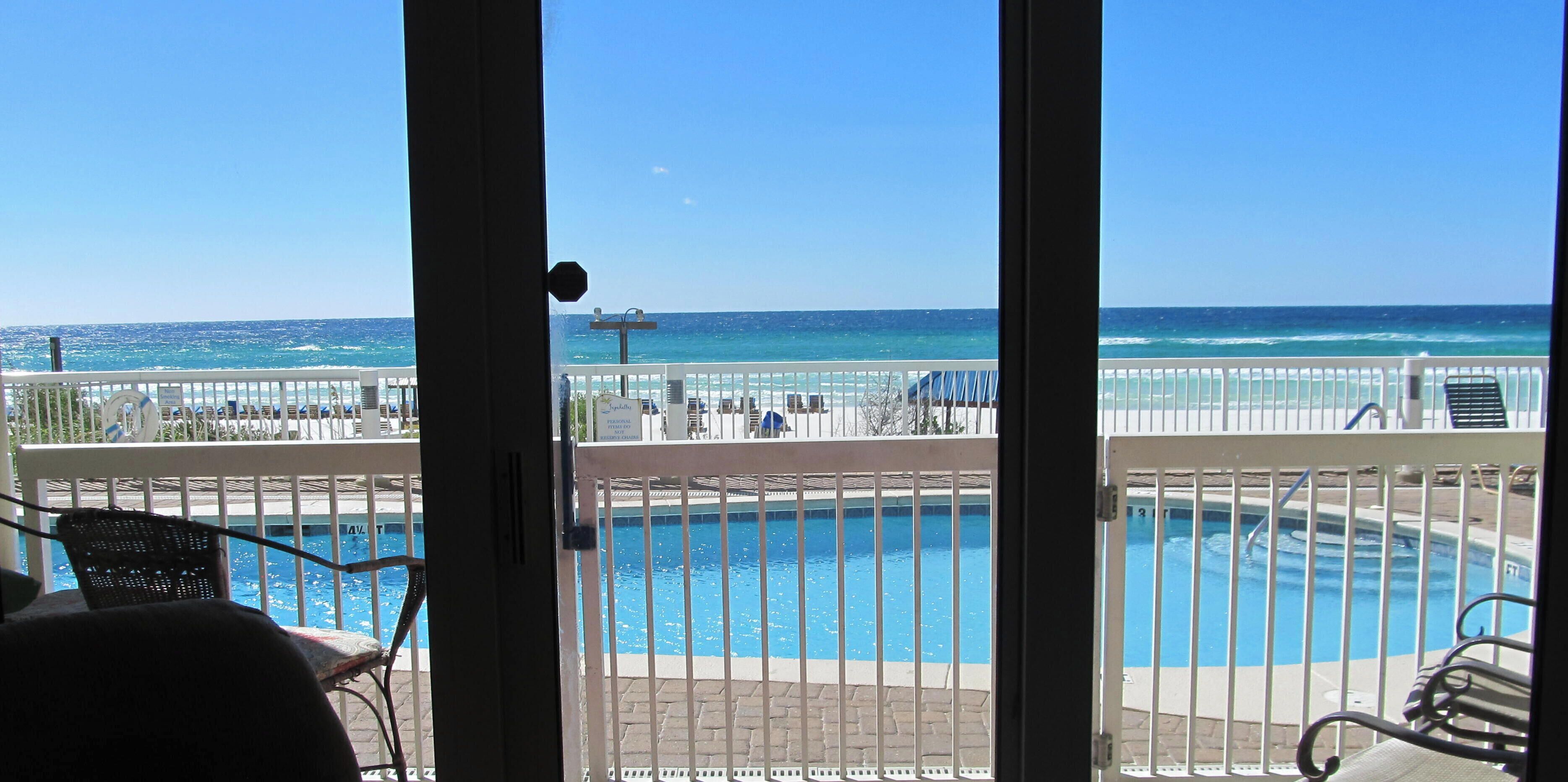 A view from a balcony overlooking a pool and the ocean.