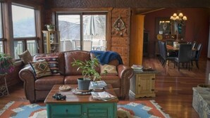 Ein gemütliches Wohnzimmer mit einer braunen Ledersofa, einem türkisfarbenen Couchtisch und einem Essbereich mit Holztisch und Stühlen.