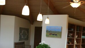 Et køkken med en træø, sort komfur, ovn og hængende pendellamper.