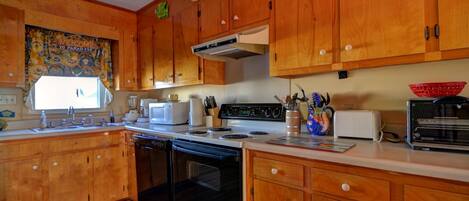 A kitchen with wooden cabinets, a stove, a microwave, and a toaster.