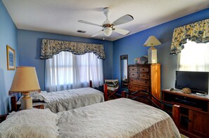 A bedroom with two beds, a ceiling fan, a TV, and a wooden dresser. - "Kitty's Place" - Beach Cottage, Dunes West, 3 Bedroom, 2 Bathroom (Holden Beach)