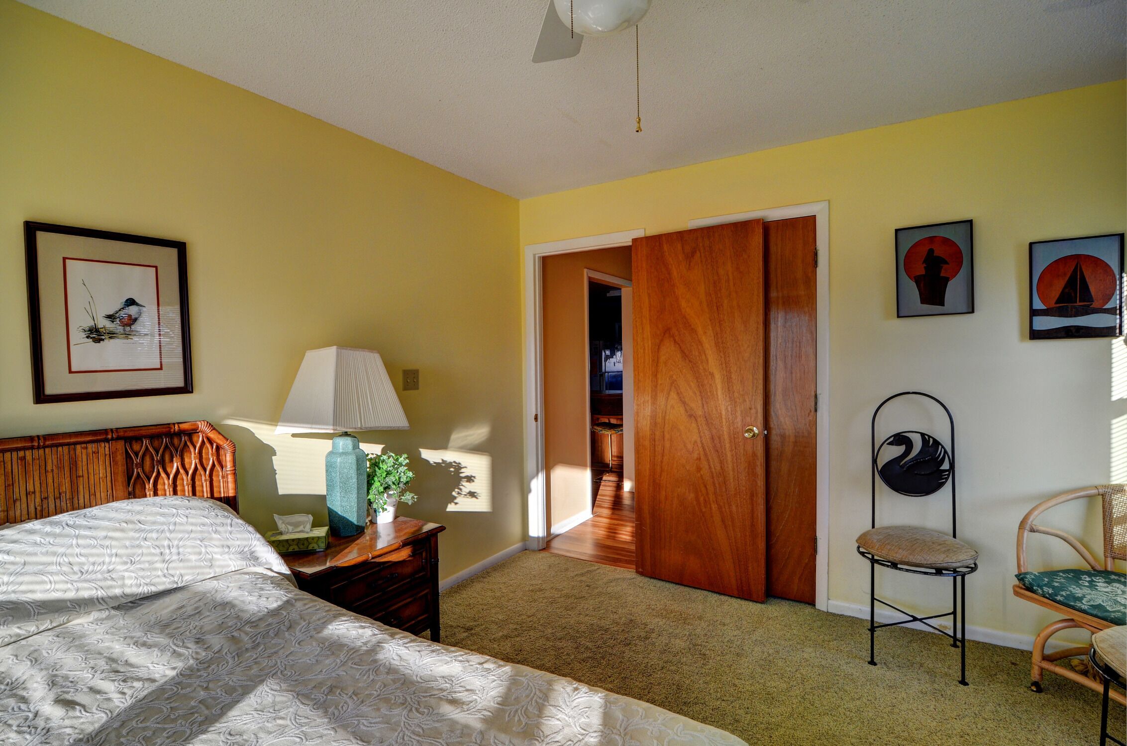 A bedroom with a bed, a nightstand, a lamp, a chair, and a door leading to another room.