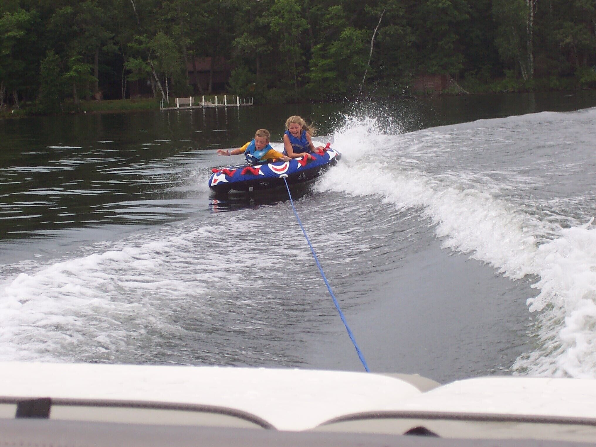A water sport activity with two people on a raft being pulled by a boat.