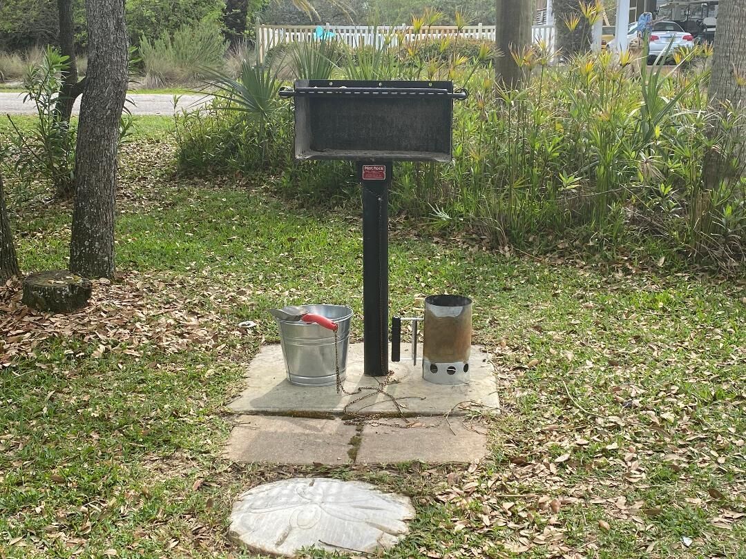 A mailbox with a metal bucket and a propane burner on a concrete base.