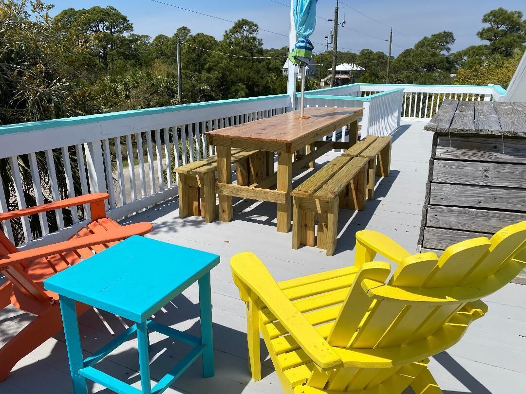 A deck with wooden furniture, including a table and chairs, and a wooden bench.