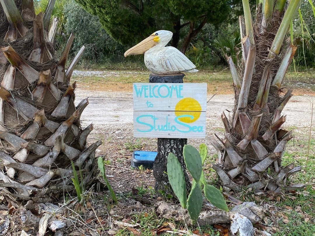 A welcome sign for Studio Sea, featuring a pelican sculpture.